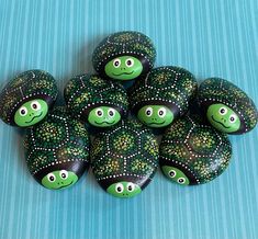 green painted rocks with black and white designs on them, sitting on a blue surface