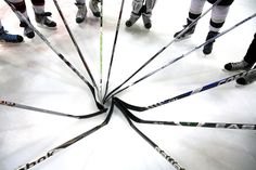 a group of people standing around each other with hockey sticks in the middle of them