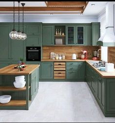 a large kitchen with green cabinets and wooden counter tops on the island in front of an oven