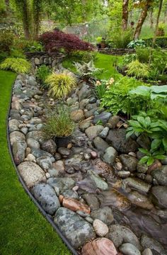 a garden filled with lots of rocks and water flowing down it's side walk