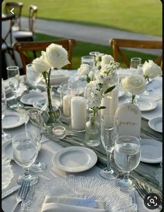 the table is set with white flowers and place settings for two people to sit at