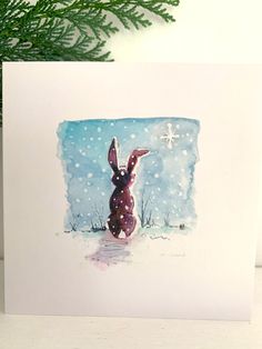 a card with a painting of a rabbit in the snow