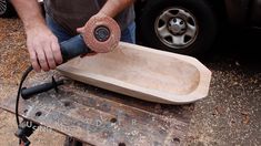 a man sanding down a wooden object with a grinder on it's side