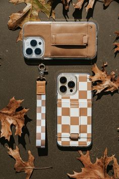 two cell phones sitting next to each other on top of leaf covered ground with leaves around them