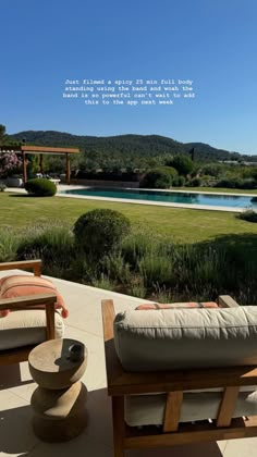 an outdoor patio with two chairs and a bench on the ground next to a pool