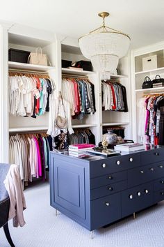 an organized closet with clothes and handbags hanging on the walls, along with a chandelier