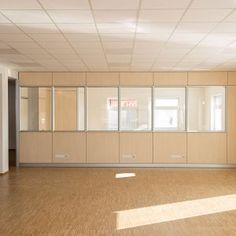 an empty room with wooden floors and white cupboards on either side of the wall