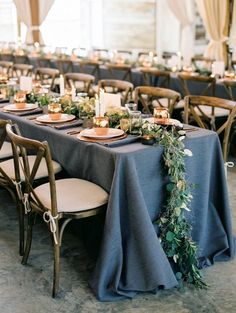 a table set up with blue linens and greenery