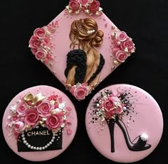 three pink buttons decorated with flowers and a woman's shoe in the center, on a black background