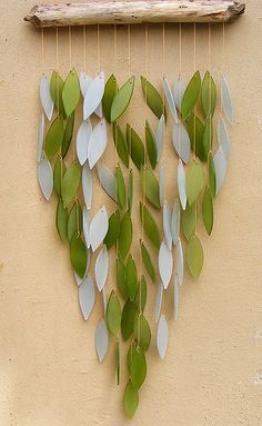 a wind chime hanging on the side of a building with leaves attached to it