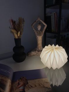 a lamp that is on top of a table next to some vases and books