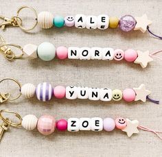 three keychains with different types of beads and charms attached to them, one has an emoticive name on it