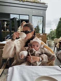 a woman holding a baby while sitting at a table