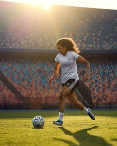 a woman is kicking a soccer ball on the field in front of an empty stadium