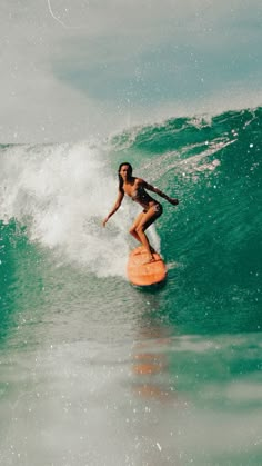 a woman riding a wave on top of a surfboard