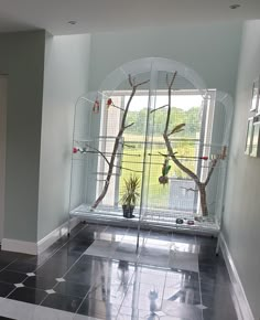 a bird cage is in the corner of a room with black tile flooring and white walls