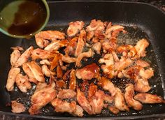 chicken wings being cooked in a skillet with sauce