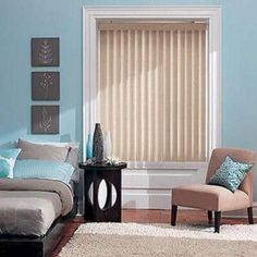 a bed room with a neatly made bed and a chair next to the window covered in blinds