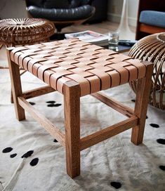 a wooden bench sitting on top of a white rug next to a wicker chair