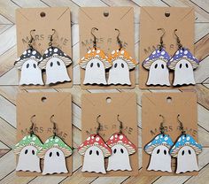 six little ghost earrings with different colors and designs are shown in front of a brown card