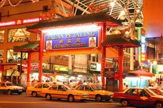 a busy city street at night with cars parked on the side and people walking around