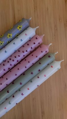 four candles are lined up on a wooden surface with hearts and flowers painted on them