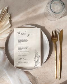 a place setting with a thank you note and gold utensils on the table