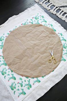 a pair of scissors sitting on top of a piece of paper next to some fabric