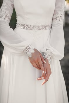 a woman in a white wedding dress holding her hands on her waist and wearing an intricate bracelet