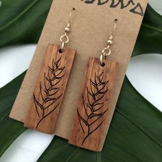 Heliconia design earring made with Hawaiian Koa Wood. These earrings are laser cut and handmade on O'ahu. Hawaiian Koa Earring is lightweight and easy to wear. The length is 6.5cm and the width is 1.5cm. The length is measured from the top of the hook. It is finished with Sterling Silver Coil Ball Earring Hooks. We repurpose the left over, discarded, or scrap koa from various woodshops and builders and use it to create our pieces. Koa is known and loved for its beautiful and complex figure, colo Woodburned Earrings, Wood Burned Gifts, Laser Engraved Earrings, Wood Jewelery, Sterling Silver Earrings Handmade, Laser Cut Jewelry, Koa Wood, Wood Bracelet, Gold Filled Earrings