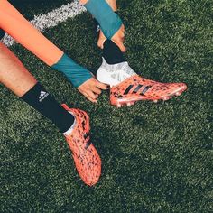 two soccer players tying their shoes on the field