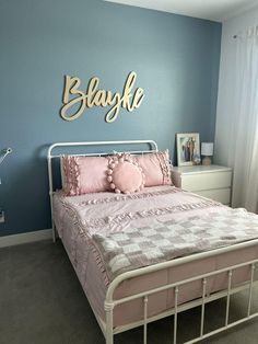 a bedroom with blue walls and pink bedding in the corner, along with a metal headboard that says slayka