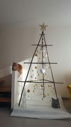 a cat sitting on top of a wooden christmas tree