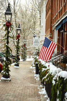 an american flag is hanging on the side of a brick building with christmas garlands