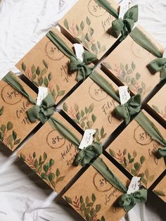 six brown boxes with green bows on them sitting on top of a white table cloth