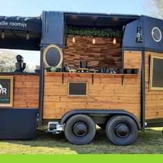 the food truck is made out of wood and has an awning over it's roof