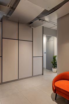 an orange chair sitting in front of a wall with white and black panels on it