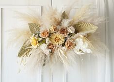 an arrangement of flowers and feathers hanging on a door