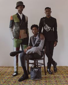 three men standing next to each other in front of a white wall wearing suits and hats