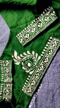 an embroidered green cloth with white designs on the front and back, sitting on top of a bed