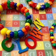 a multi - colored beaded necklace with letters and numbers is on a colorful checkered tablecloth