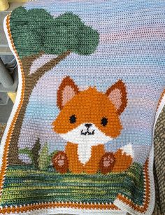 a crocheted blanket with an image of a little fox on it's back