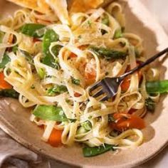 a plate full of pasta and vegetables with a fork