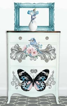 a blue and white dresser with a butterfly painted on the front, next to a framed photo