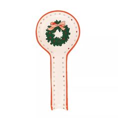 an orange and white spoon with a christmas wreath on the front is holding a red ribbon