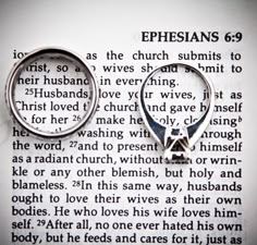 two silver rings sitting on top of an open bible page with the word ephesians printed in it