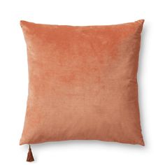 an orange velvet pillow with a tasselled edge