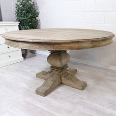 a wooden table sitting on top of a hard wood floor next to a white brick wall