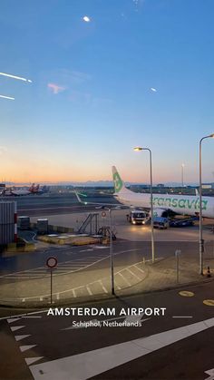 an airport with airplanes parked on the tarmac at sunset or dawn, as seen from across the street