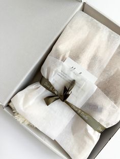 two folded towels in a box with ribbon on the top and one wrapped in white paper